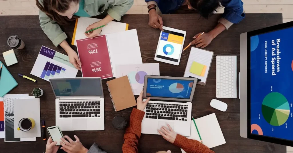 Un equipo diverso que colabora en estrategias de marketing digital en un escritorio, utilizando computadoras portátiles y tabletas.