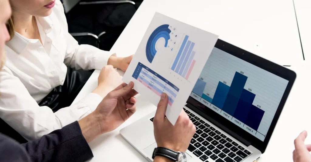 Profesionales de negocios discutiendo gráficos y cuadros de datos en un entorno de oficina moderno.