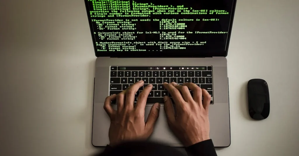 desde arriba, un programador anónimo con una sudadera negra trabaja con un código de software en una netbook moderna y escribe en el teclado de su espacio de trabajo.