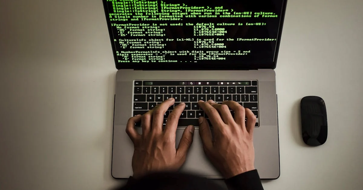 desde arriba, un programador anónimo con una sudadera negra trabaja con un código de software en una netbook moderna y escribe en el teclado de su espacio de trabajo.