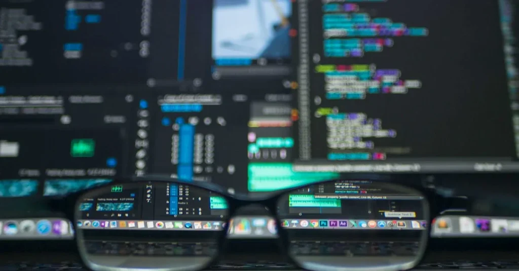 Gafas que reflejan el código de computadora en un monitor, ideales para temas de tecnología y programación.